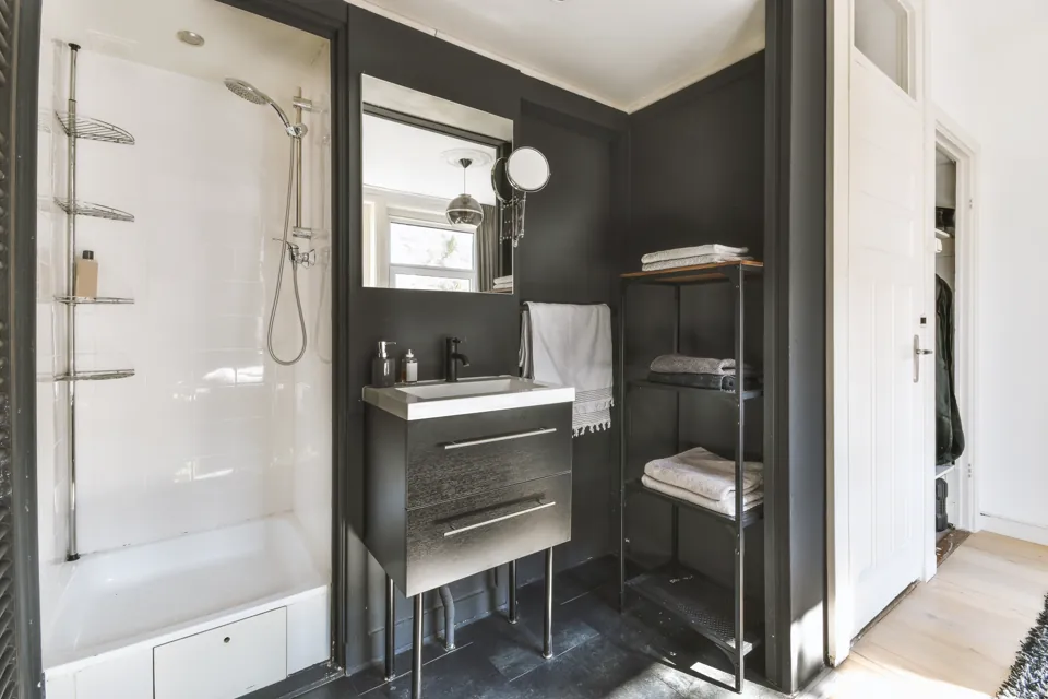 Bathroom with a glass shower, dark tile, and a vanity