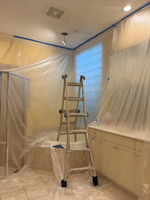 Bathroom surfaces protected with plastic and tape during painting preparation