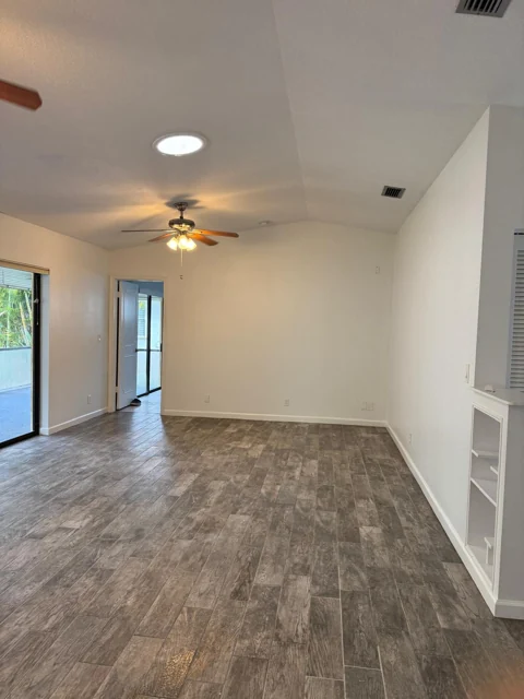 Bright interior with white walls, a vaulted ceiling, and wood-look tile flooring